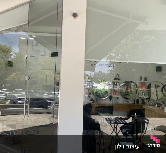 וילון לבן תלוי בחלק העליון של חלון זכוכית